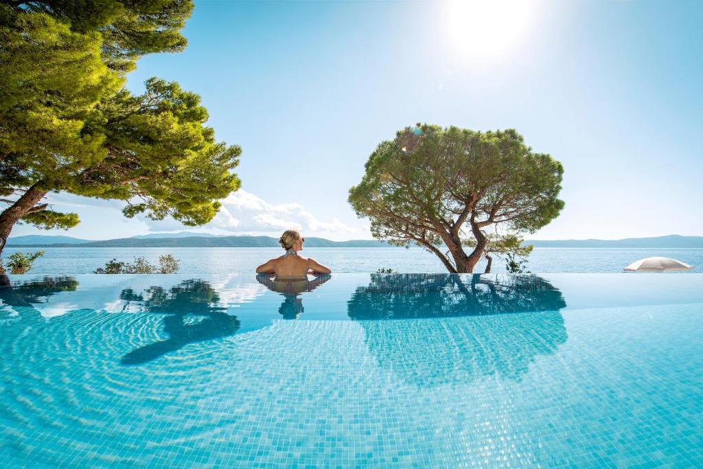 uma pessoa sentada na piscina de beiral infinito de um resort em TUI BLUE Makarska - Adults Only em Igrane