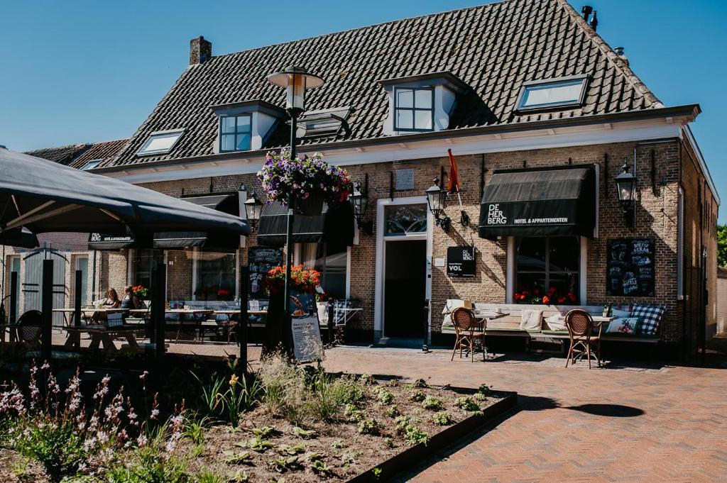 een gebouw met een tafel en stoelen ervoor bij De Herberg in Renesse