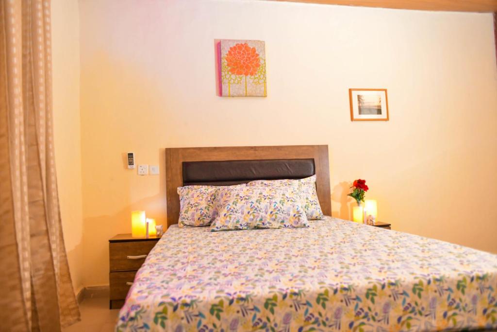 a bedroom with a bed and two candles on tables at Living Green APARTMENTS AIRPORT PICK UP in Benin City