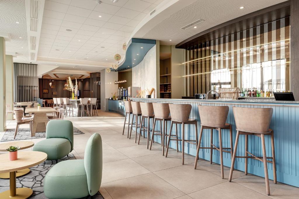 a lobby with a bar with chairs and tables at B&B HOTEL Lille Lillenium Eurasanté in Lille