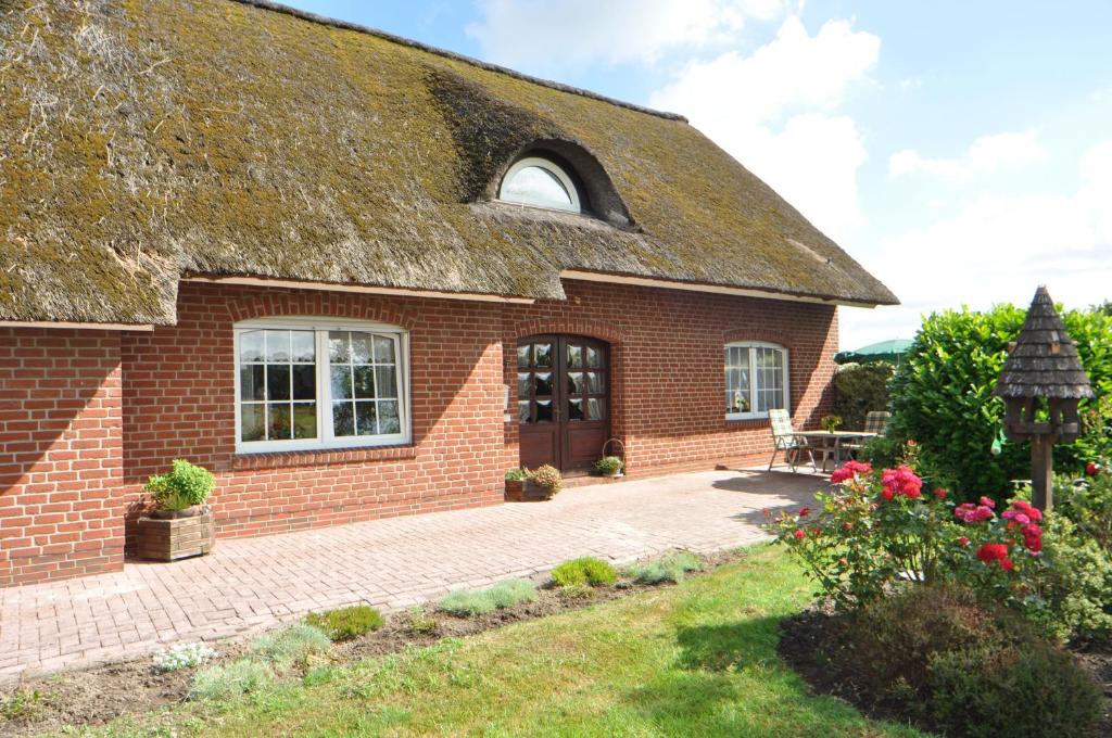 a brick house with a thatched roof at Ferienwohnung Landliebe 65347 in Moormerland