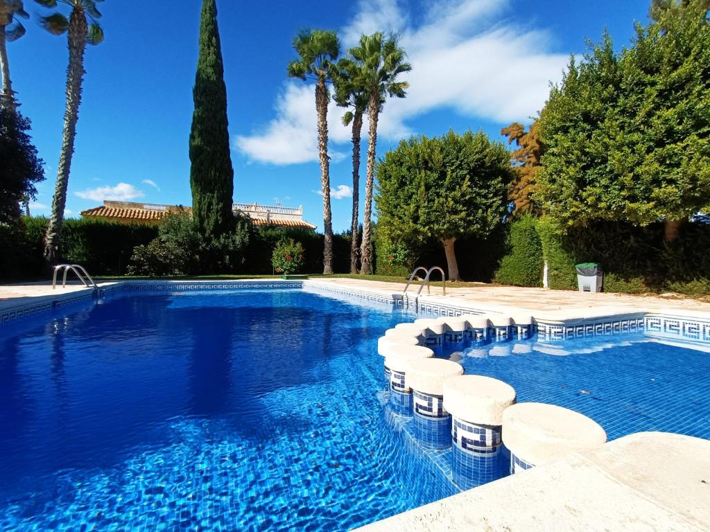 a swimming pool with chairs and palm trees at Butterfly Bungalow - 9009 in Los Alcázares