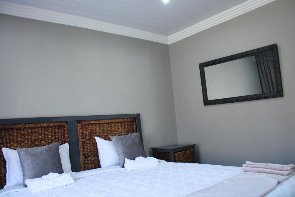 1 dormitorio con 1 cama blanca grande y espejo en The Villa 442 en Pretoria