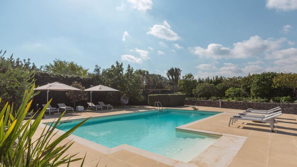 a swimming pool with chairs and umbrellas in a yard at VILLA KIMIA 8, Emma Villas in Acireale