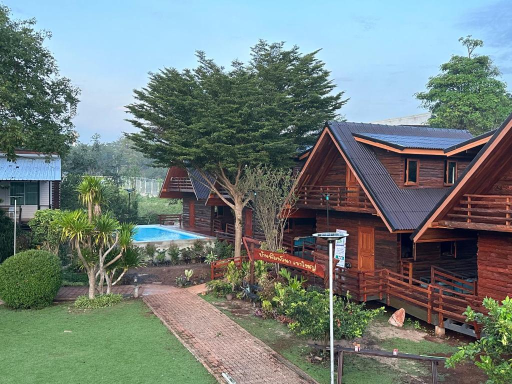 a log house with a swimming pool in front of it at พิมพ์วนา เขาใหญ่ in Nakhon Ratchasima