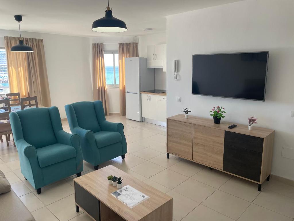 a living room with two chairs and a flat screen tv at Apartamentos Tao Laia in Puerto del Rosario