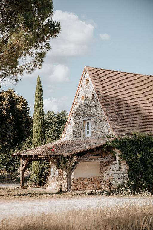 an old stone house with a window and a tree at Domaine St-Amand in Saint-Amand-de-Coly