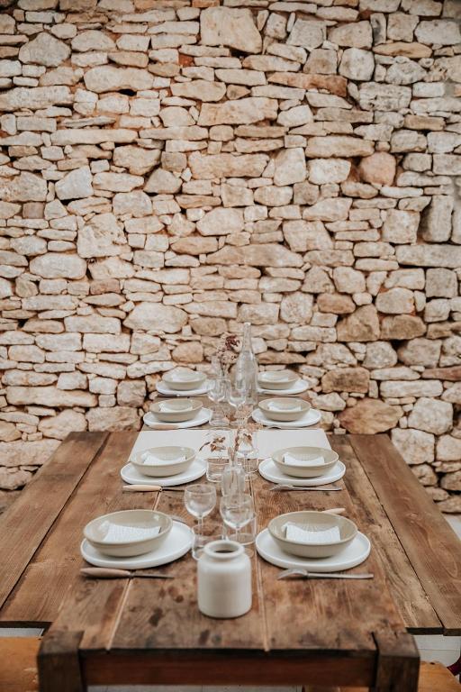 a wooden table with white plates and wine glasses at Domaine St-Amand in Saint-Amand-de-Coly