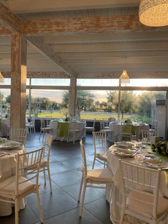 uma sala de jantar com mesas e cadeiras brancas em Hotel Villa Ruggiero em Brusciano
