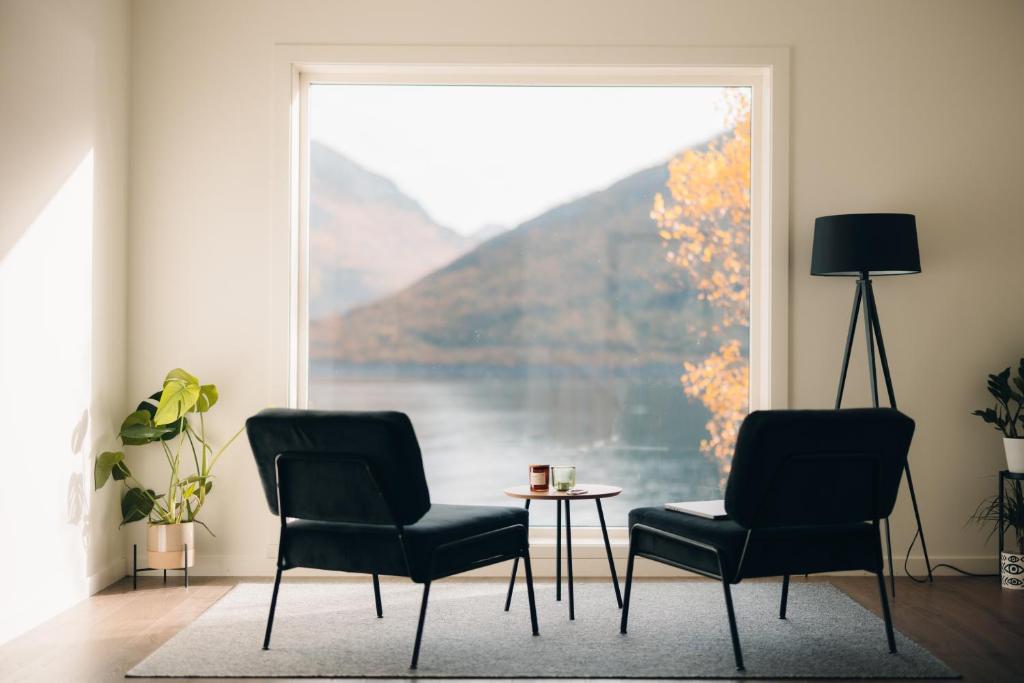 Fjordgård的住宿－Polar Panorama Lodge，窗户客房内的两把椅子和一张桌子