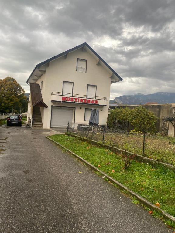 une maison blanche avec garage sur le côté d'une route dans l'établissement Maison 5 chambres 2 salons, à Saint Pierre en Faucigny