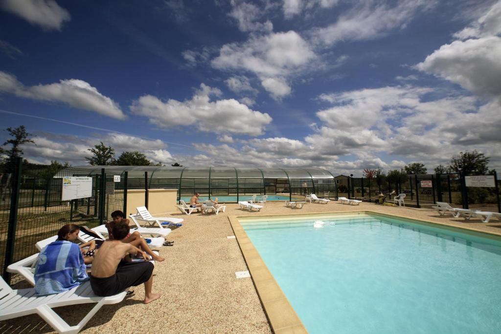 a group of people sitting in chairs by a swimming pool at Terres de France - Les Hameaux de Miel in Beynat