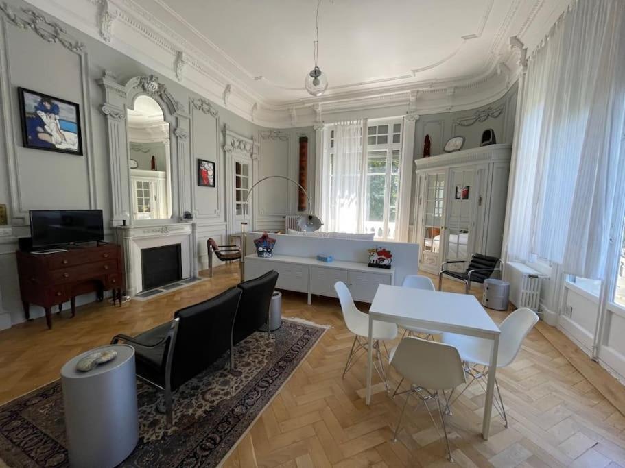 een grote woonkamer met een tafel en stoelen bij Suite Célestine Palace Excelsior vue lac in Aix-les-Bains