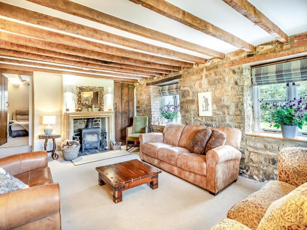 uma sala de estar com mobiliário de couro e uma parede de pedra em Bridge Cottage em High Ham