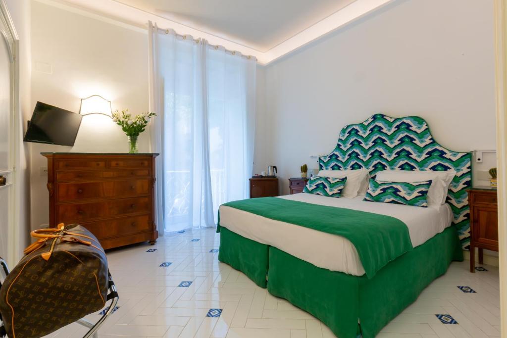 a bedroom with a green and white bed and a dresser at Hotel Villa Di Sorrento in Sorrento