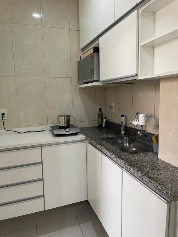 una cocina con armarios blancos y fregadero en Poket em Vila Isabel Barão de Cotegipe 204, en Río de Janeiro