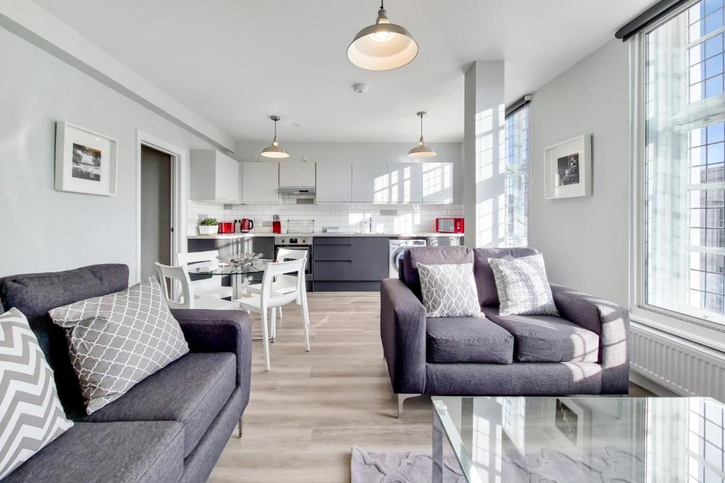 a living room with two couches and a kitchen at Roomspace Serviced Apartments - Brewers Lane in Richmond