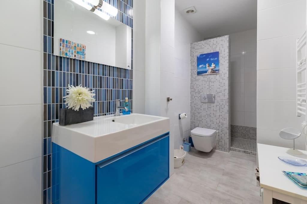 a bathroom with a blue and white sink and a toilet at ApartUP Patacona Azzure in Valencia