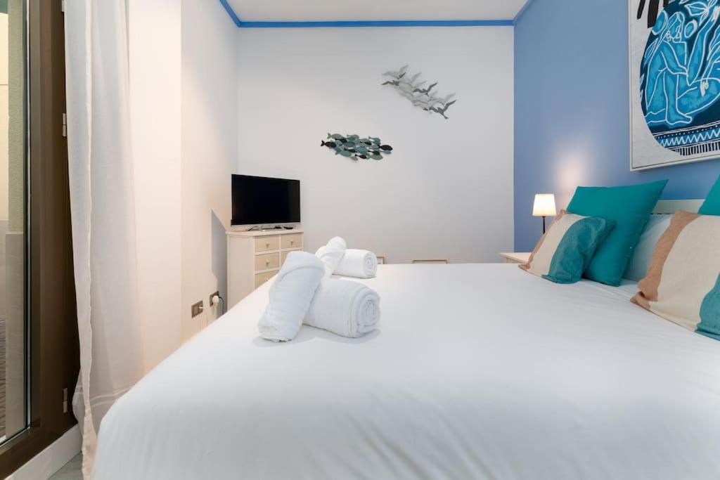 a bedroom with a white bed with towels on it at ApartUP Patacona Azzure in Valencia