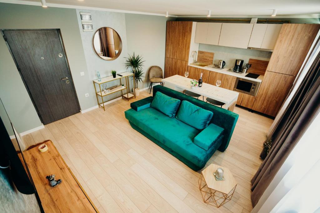 sala de estar con sofá verde y cocina en Smart Studio 76 en Onești