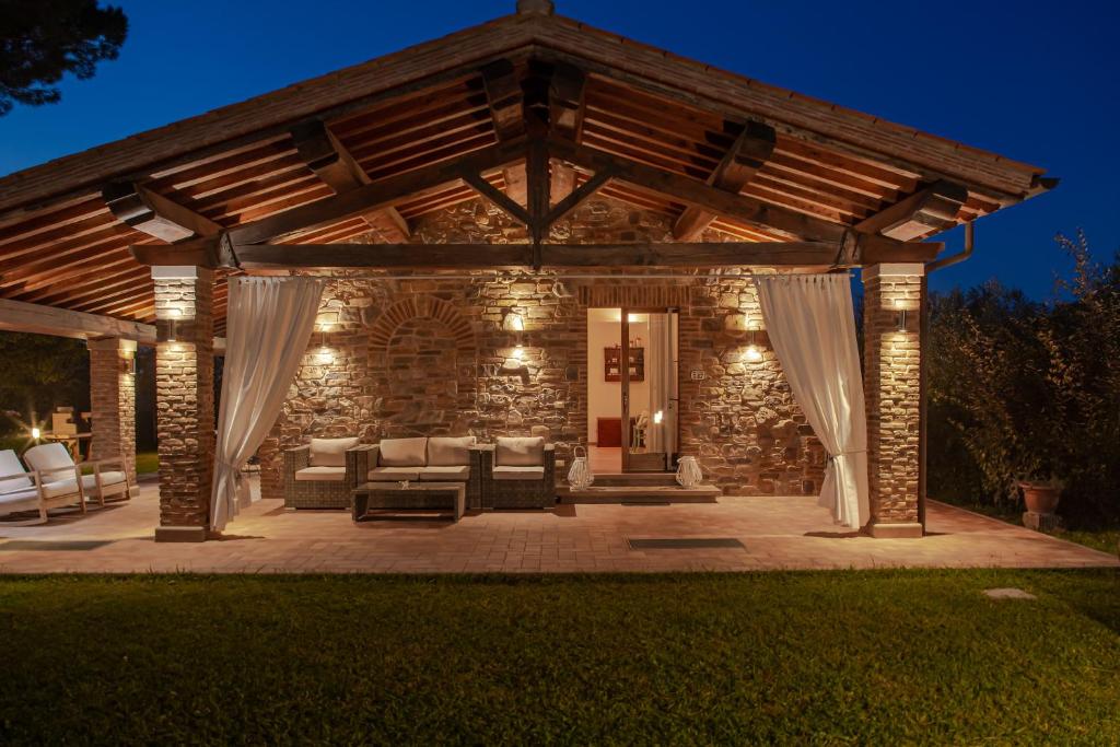 un patio de piedra con un pabellón por la noche en Villa Siloral Blu, en Donoratico