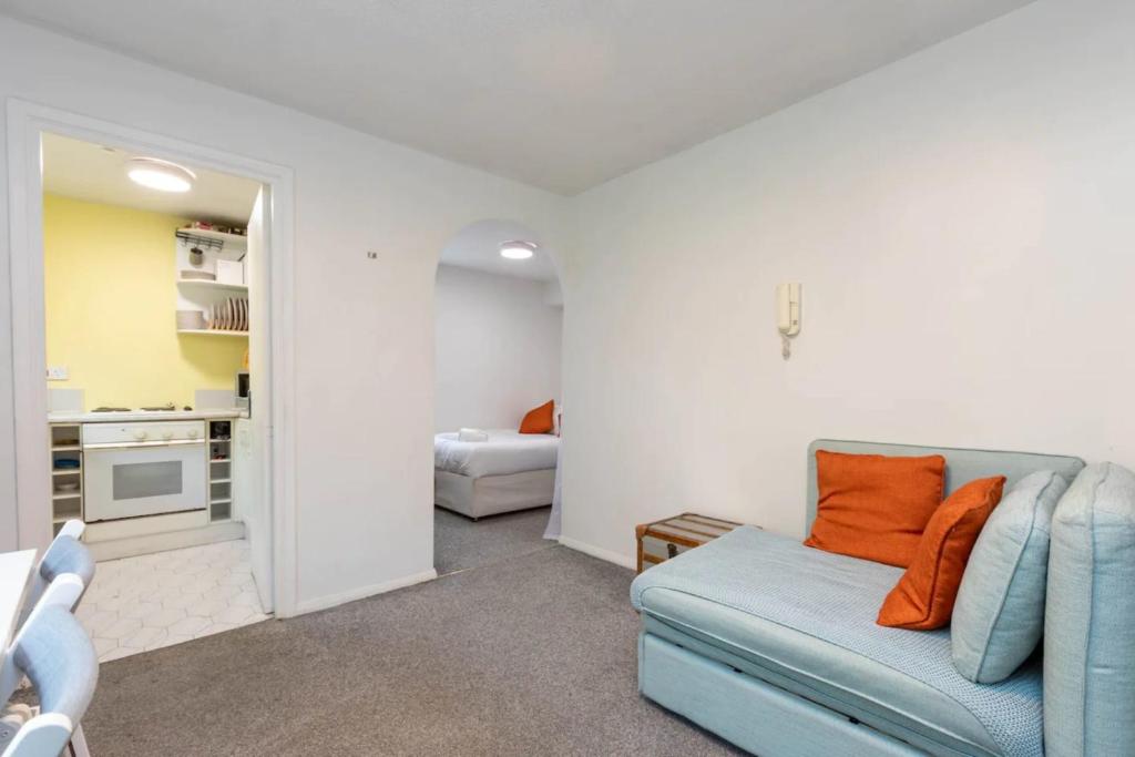 a living room with a blue couch and a kitchen at 1 Bedroom Light Studio Flat in Surrey Quays in London