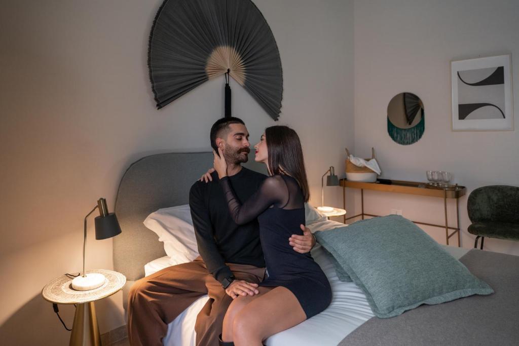 um homem e uma mulher sentados numa cama em Palazzo Marzionna em Polignano a Mare