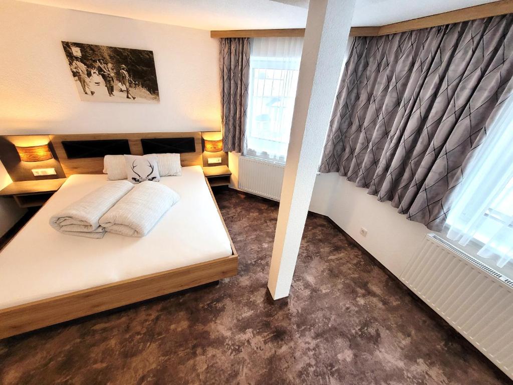 1 dormitorio con 1 cama y 2 ventanas en Apart Garni Jägerheim, en Kappl