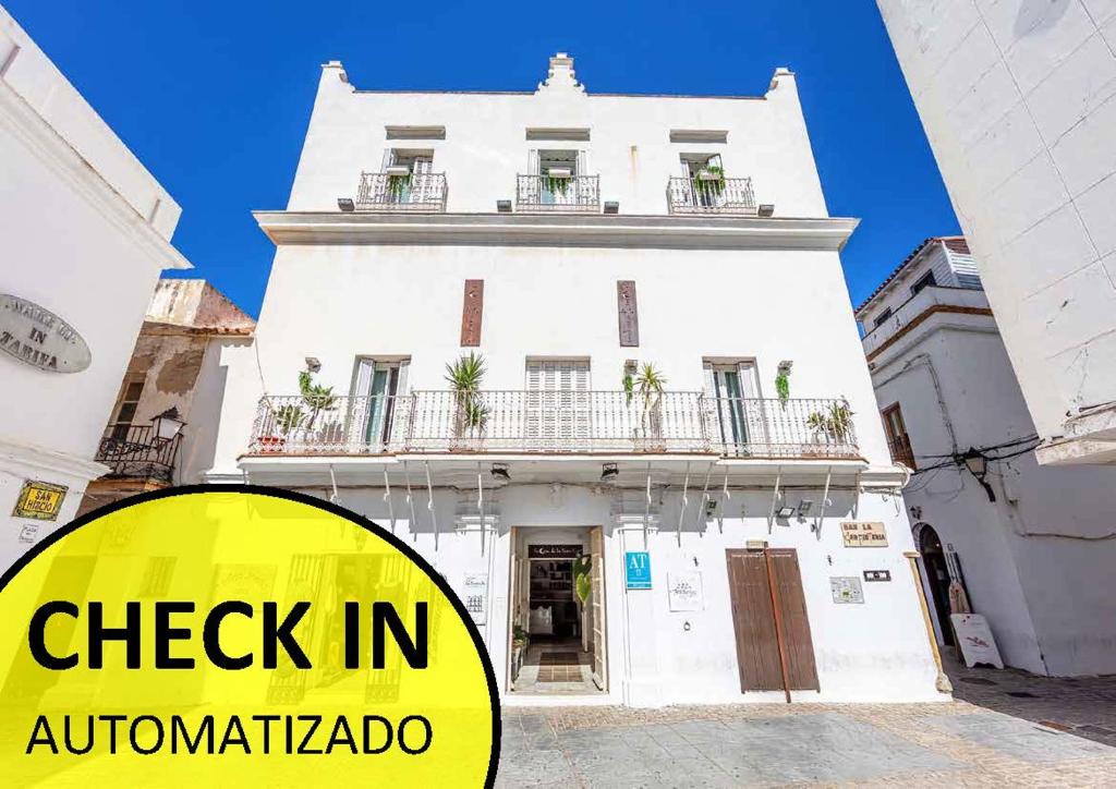 un edificio blanco con un cartel que lee check in antigua en La Casa de la Favorita, en Tarifa