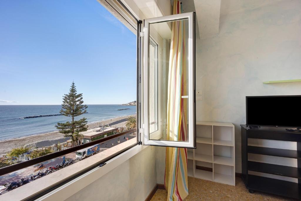 um quarto com uma janela com vista para a praia em Casa Fronte mare em Arma di Taggia