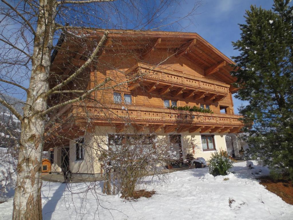 a large wooden house with a balcony in the snow at Ferienhaus Veronika in Neukirchen am Großvenediger