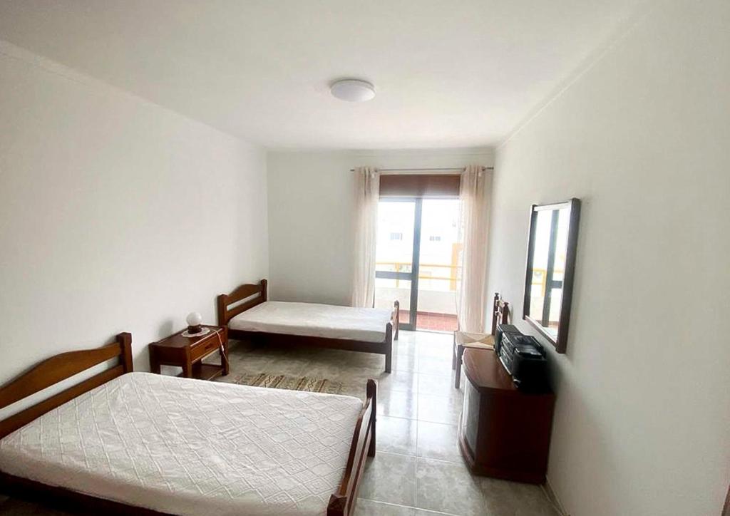 um quarto com 2 camas, um espelho e uma janela em Algarve Apartment Manta Rota em Vila Nova de Cacela
