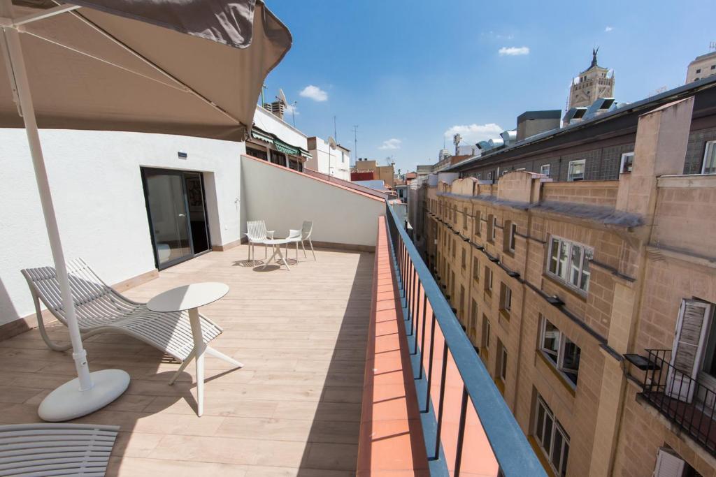 een balkon met stoelen en een parasol op een gebouw bij Apartamentos Centro Jardines in Madrid