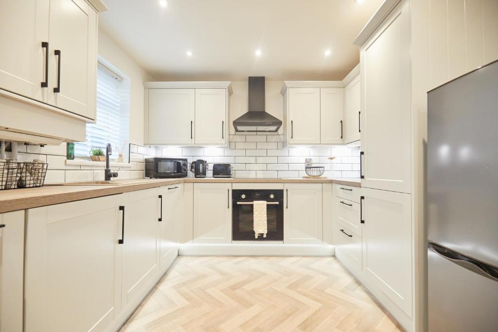 a kitchen with white cabinets and a stove at Luxurious and Modern 3 Bed townhouse with Parking in Norwich
