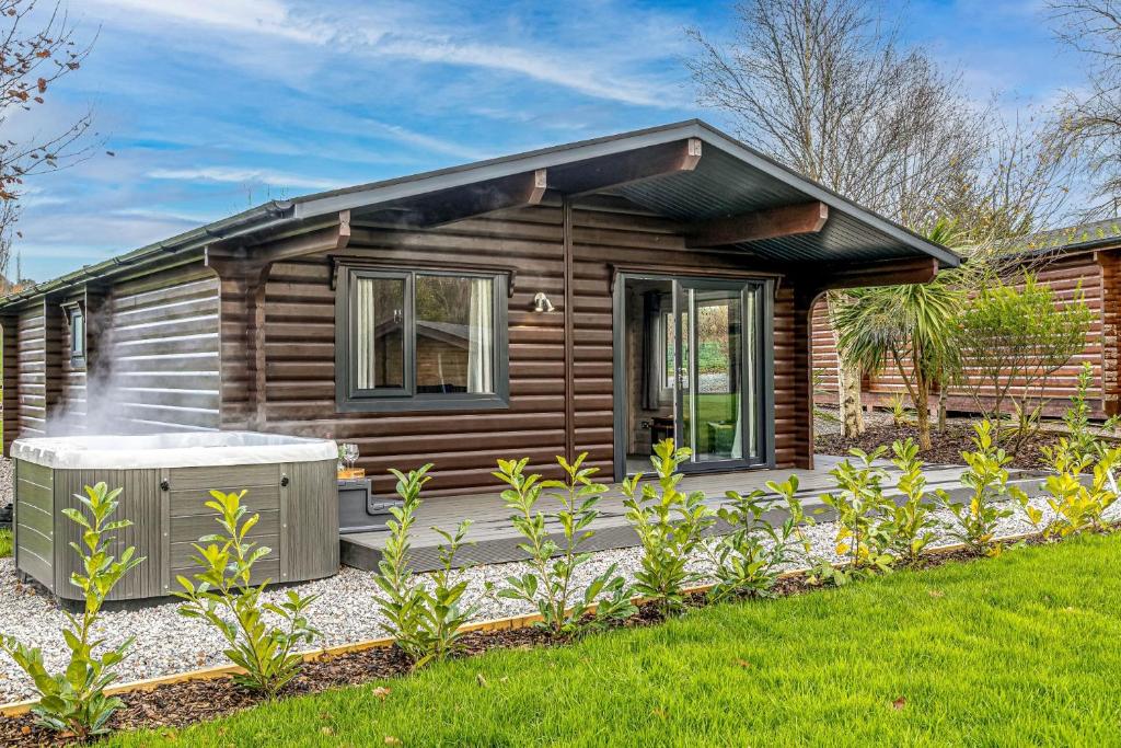 a log cabin with a hot tub in the yard at Chestnut, 6 Fingle Glen Lodges in Holcombe Burnell