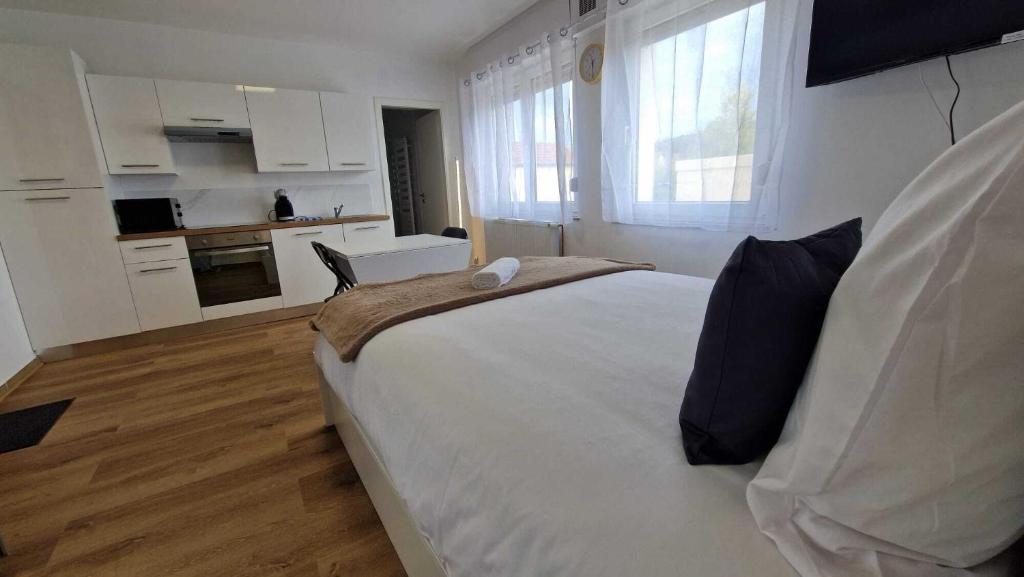 a bedroom with a large white bed and a kitchen at La Villa du General Patton in Thionville