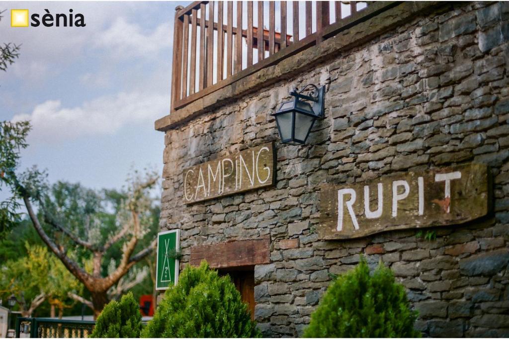 - un bâtiment en briques avec un panneau indiquant la rue dans l'établissement CAMPING SÈNIA RUPIT, à Rupit i Pruit