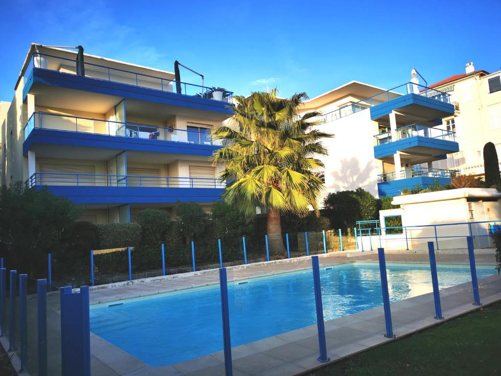 - une piscine en face d'un bâtiment avec un palmier dans l'établissement Residence Paradis Bleu, à Cannes