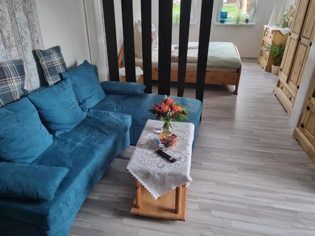 ein Wohnzimmer mit einem blauen Sofa und einem Tisch in der Unterkunft Fewo-Kreiensen in Einbeck