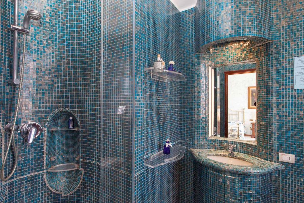 La salle de bains est pourvue de carrelage bleu, d'un lavabo et d'un miroir. dans l'établissement Holiday home in Quartu Sant'Elena 22916, à Flumini di Quartu