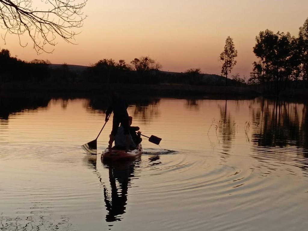 a person in a kayak on a lake at sunset at Beynespoort Farm in Cullinan