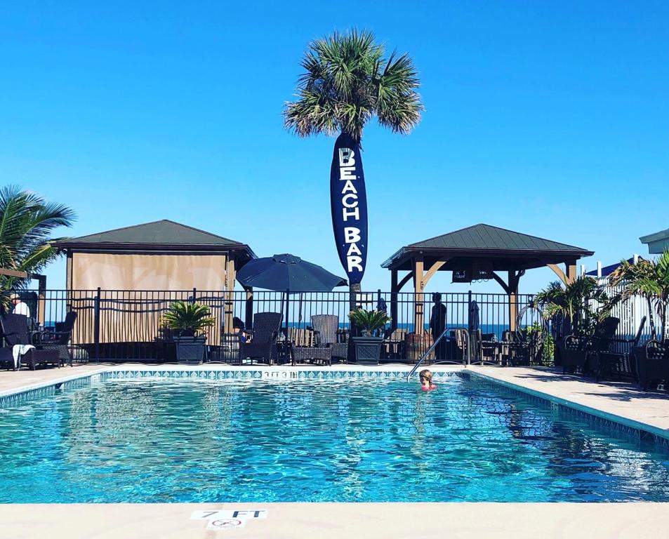 une personne se baignant dans une piscine avec un palmier dans l'établissement Bleu Beach Resort, à Indialantic