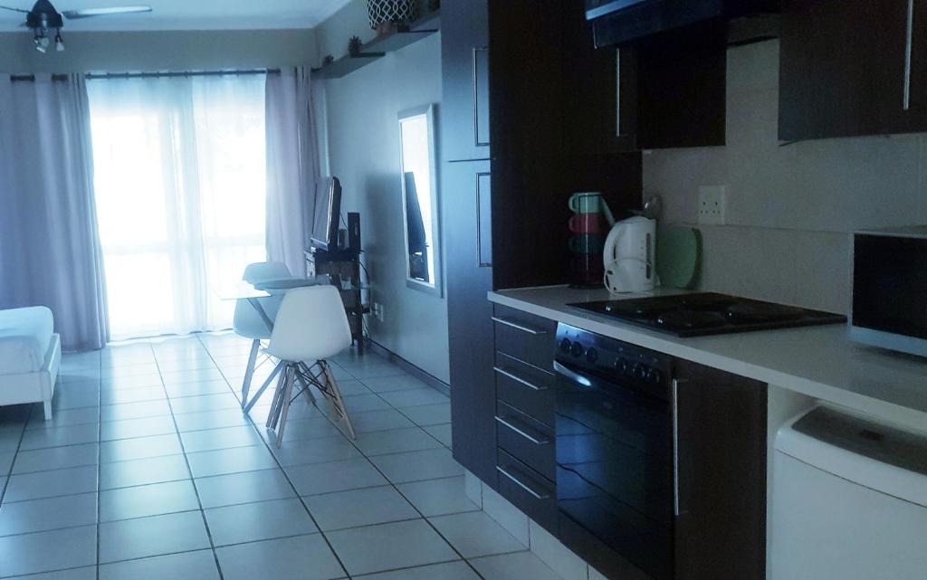 a kitchen with black cabinets and a white tile floor at Samtip Sunset in Johannesburg