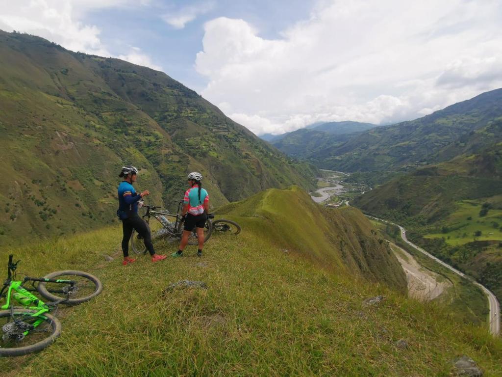 two people standing on a hill with their bikes at Refugio Explora Verde in Choachí