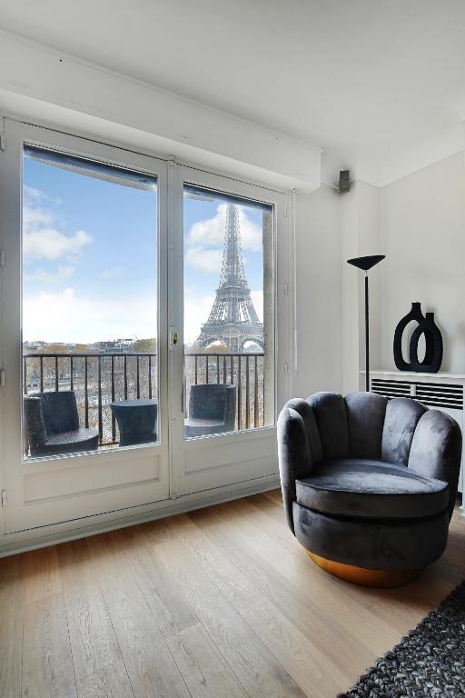 - un salon avec une chaise et une vue sur la tour Eiffel dans l'établissement Wonderfull apartment - 1BR-6P - Eiffel Tower, à Paris