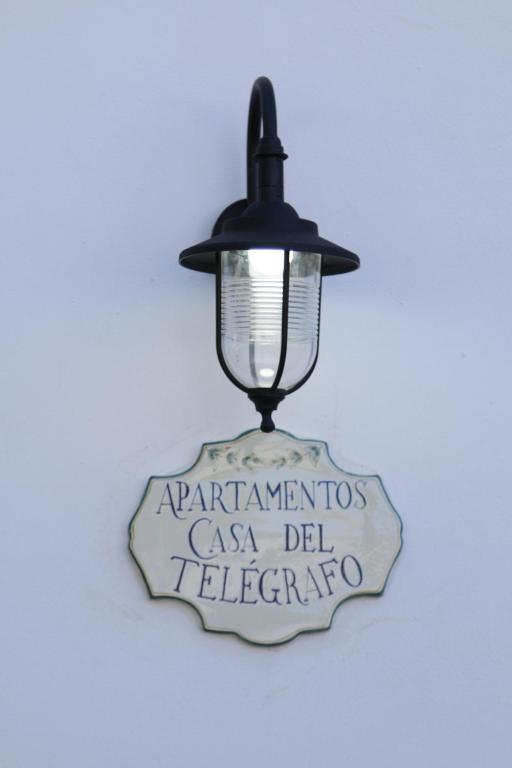 un letrero colgado en una pared con una lámpara en Casa del Telegrafo, en Utrera
