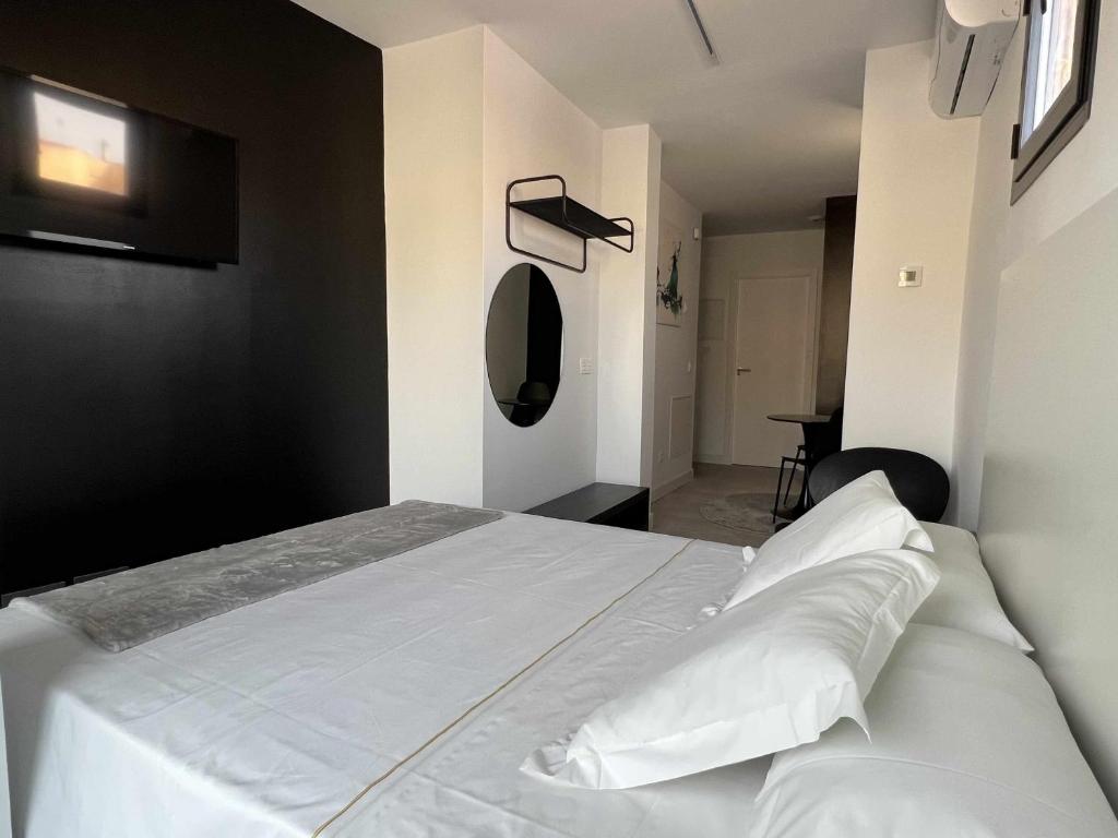 1 dormitorio con 1 cama con sábanas y almohadas blancas en Flamenco modern & luxury, en Málaga