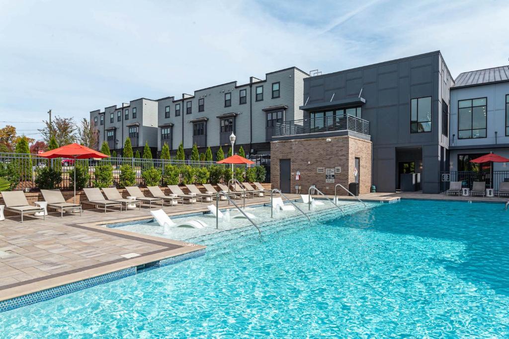 a swimming pool with chairs and a building at Kasa FreeMoreWest Charlotte in Charlotte