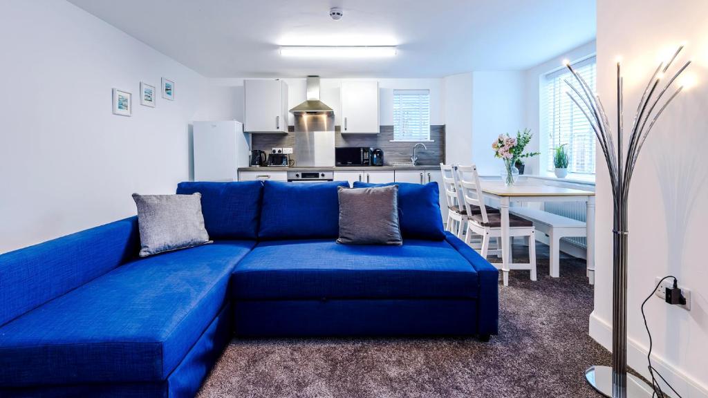 a blue couch in a living room with a kitchen at Stylish Modern Apartment in Conwy in Conwy