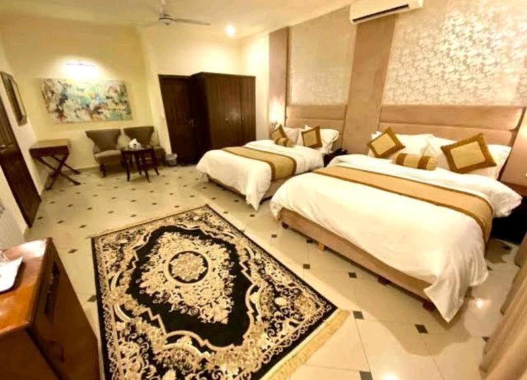 una camera d'albergo con due letti e un tavolo di Imperial lodges a Islamabad